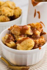white bowl of bread pudding with caramel sauce