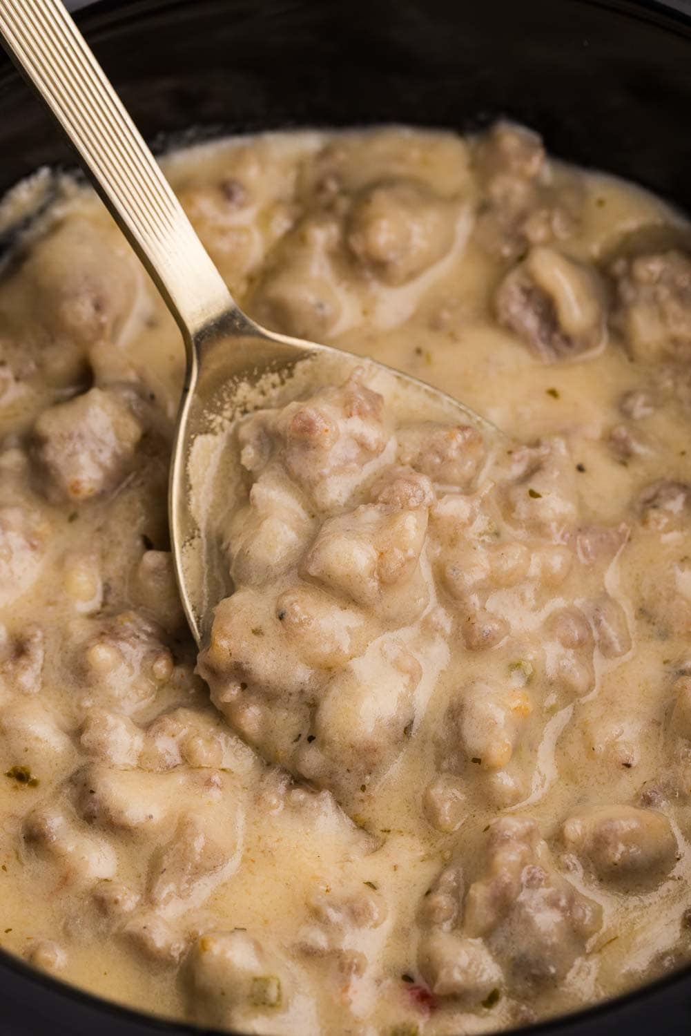 Close up image of Slow Cooker Sausage Cheese Dip being stirred