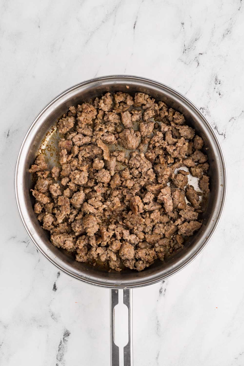 Browned sausage, broken into pieces, placed in a stainless steel skillet