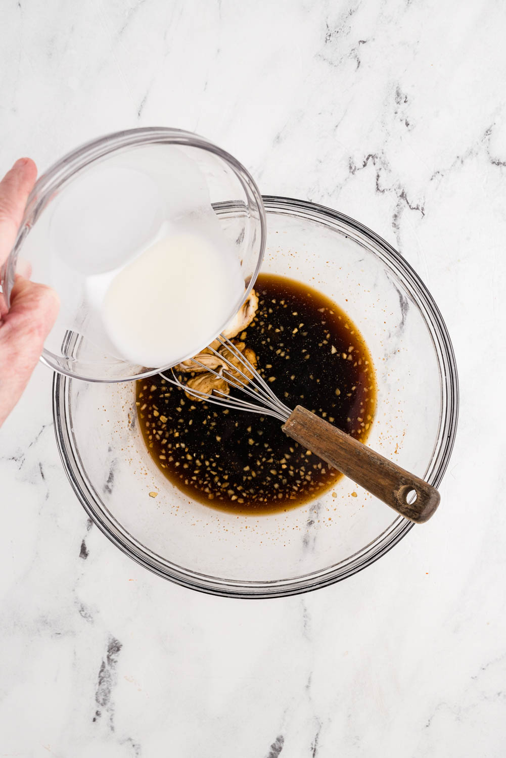 cornstarch mixture being poured and whisked into soy sauce mixture in bowl