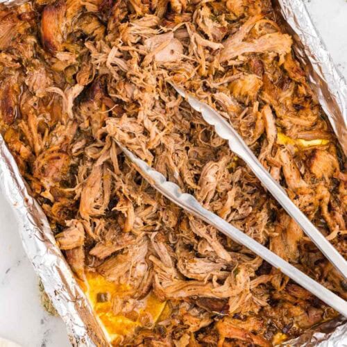 Slow Cooker Carnitas cooked and served on large baking dish covered in foil
