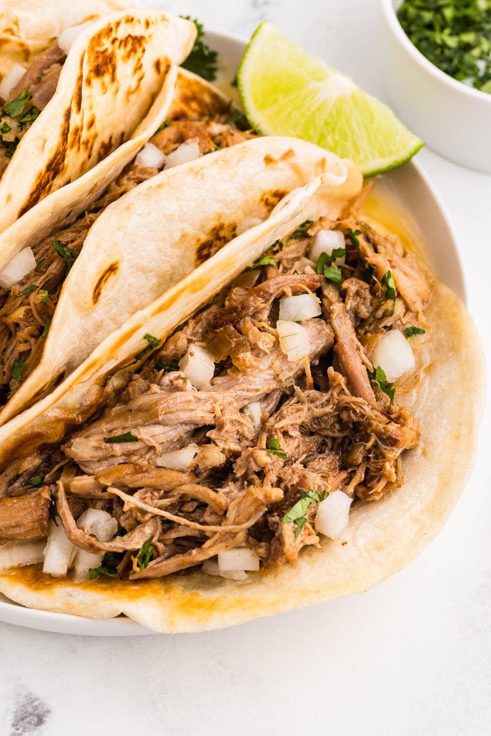Close up of slow cooker carnitas served and garnished with lime