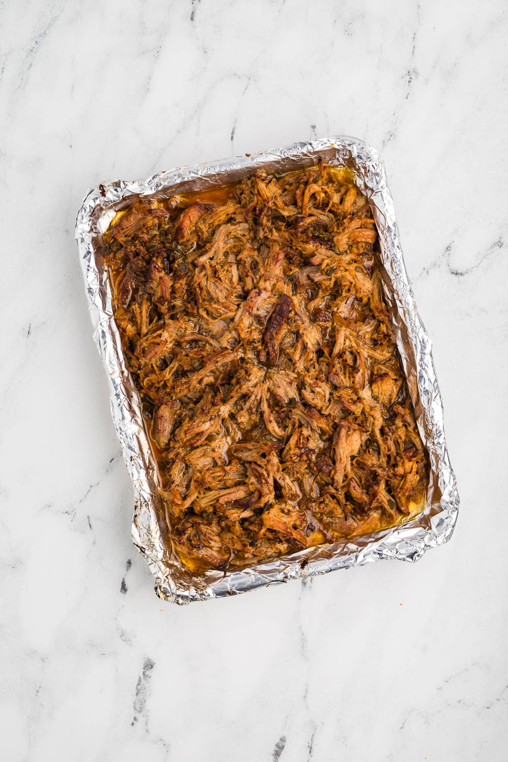 Slow Cooker Carnitas cooked and served on large baking dish covered in foil