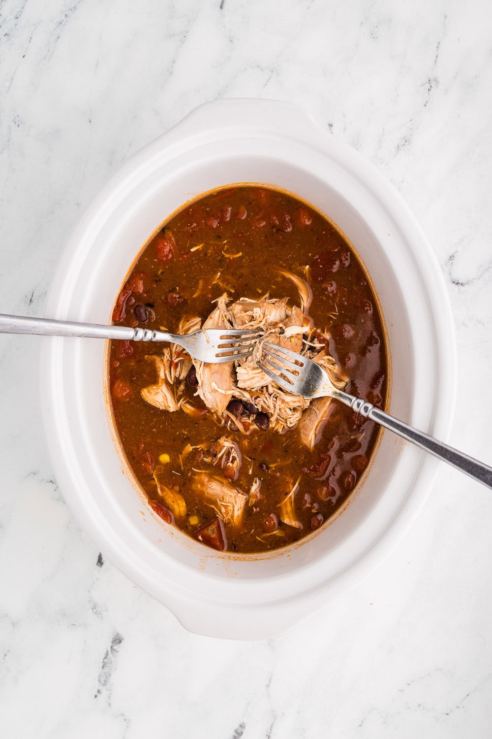 Slow Cooker Creamy Chicken Enchilada Soup with chicken being shredded inside