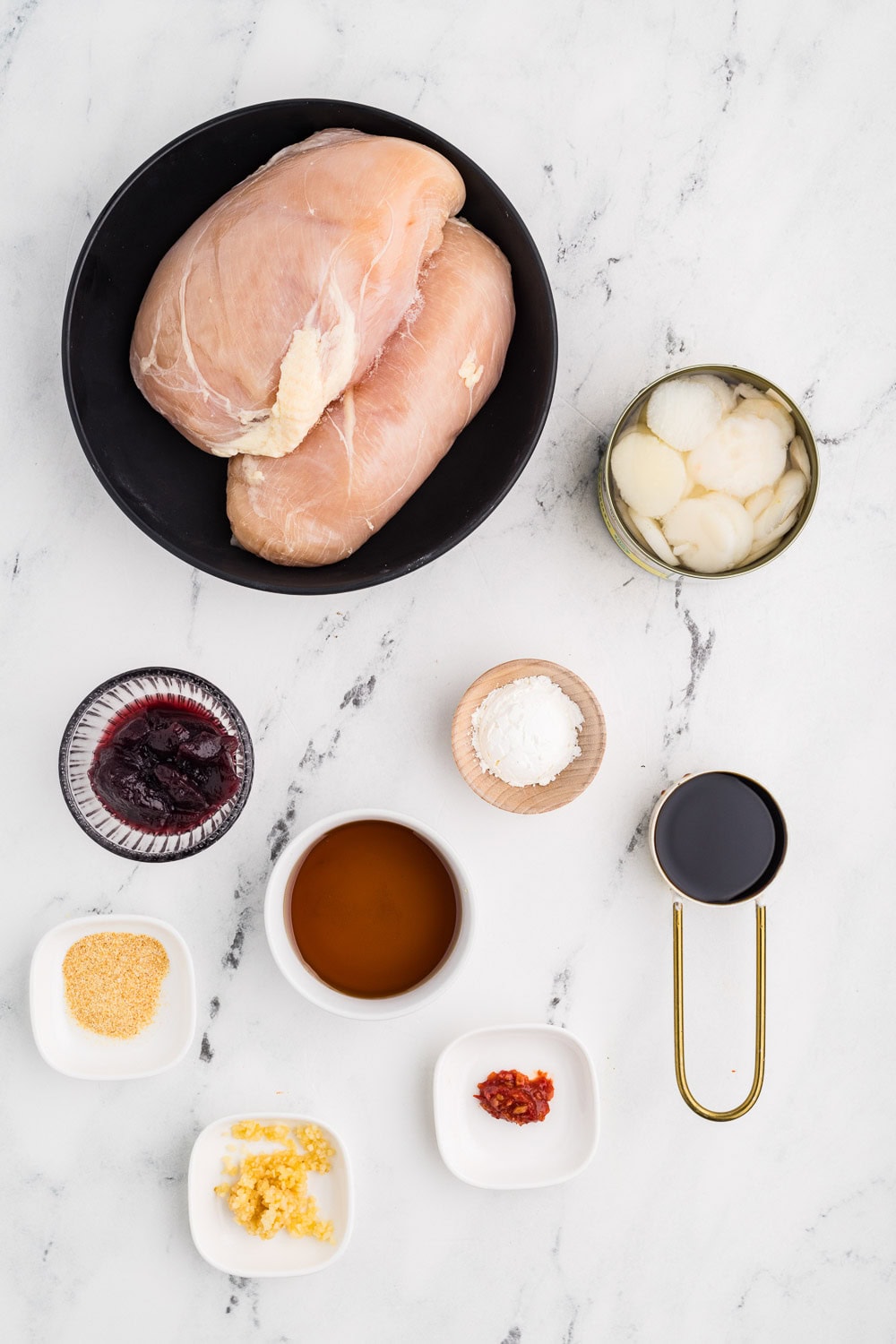 Ingredients like 1 pound boneless skinless chicken breasts 8 ounces can water chestnuts 1/4 cup soy sauce 1/4 cup honey 2 tablespoons blackberry jam seedless 1 tablespoon cornstarch 2 teaspoons minced garlic 1/2 teaspoon chili garlic sauce 1/2 teaspoon garlic powder arranged in small dishes on counter ready to prepare recipe