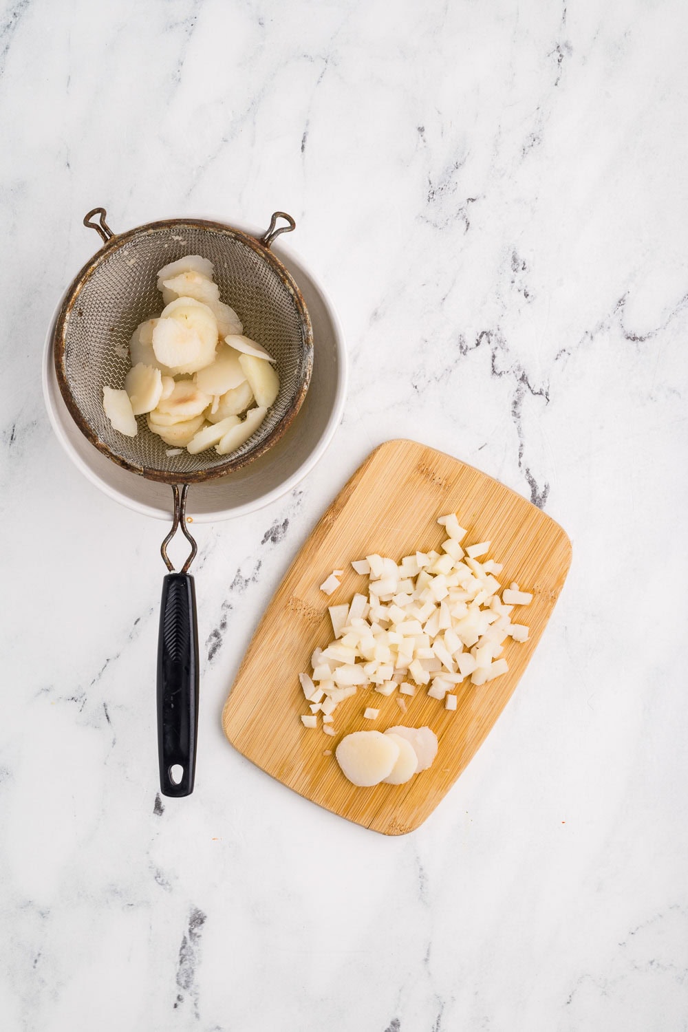 Water chestnuts some in strainer and some on a cutting board in process o of being diced