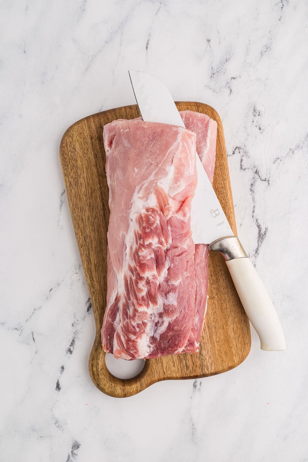 Pork Tenderloin being butterfly cut on wooden cutting board
