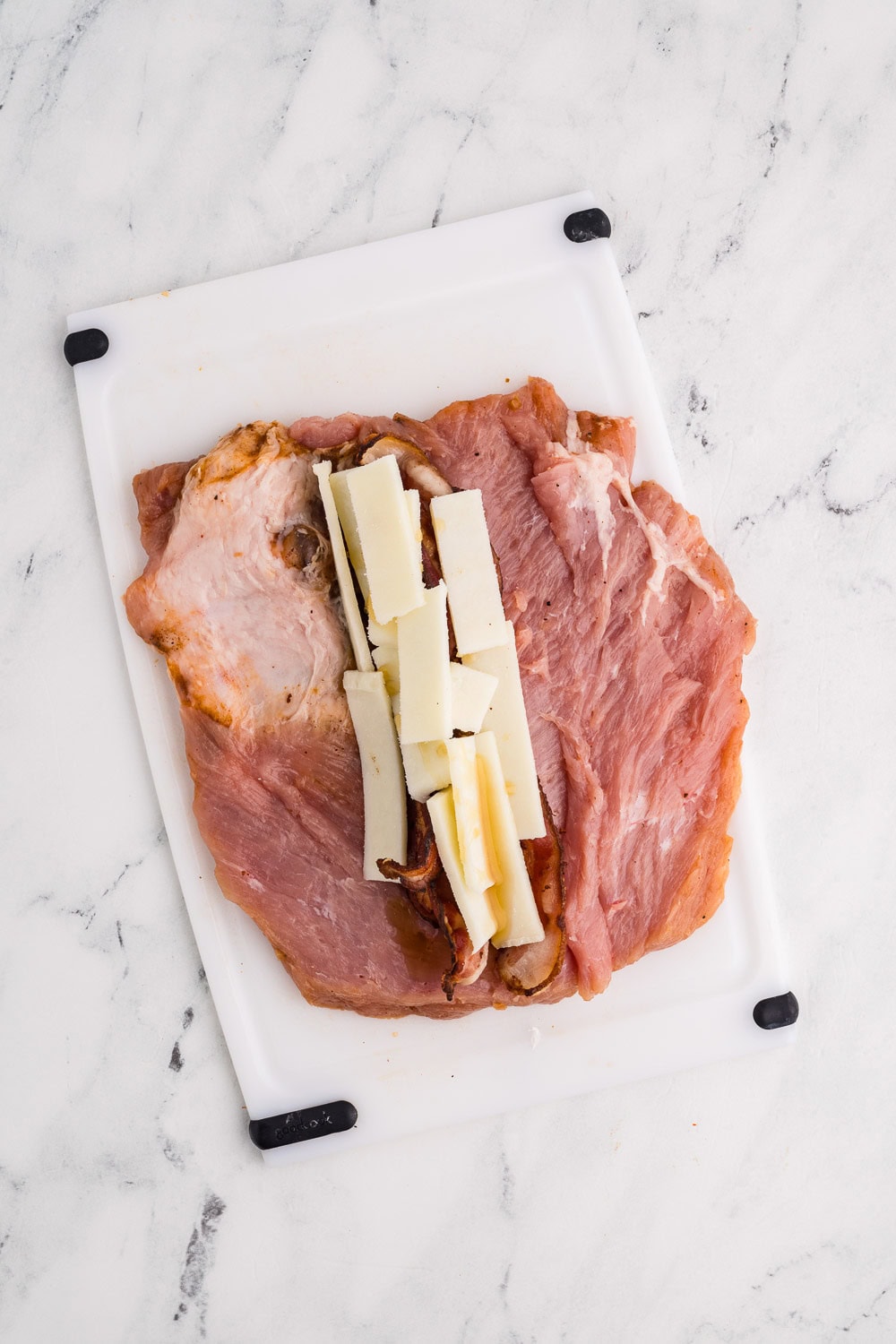 Butterflied pork tenderloin with bacon, cheese, and honey down center of pork and ready to roll