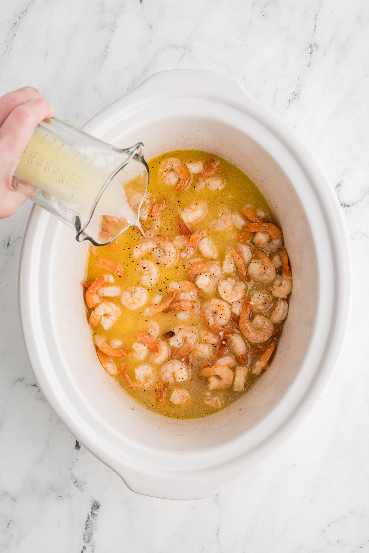 Add shrimp, olive oil, butter, wine, garlic, salt, pepper and red pepper flakes to slow cooker
