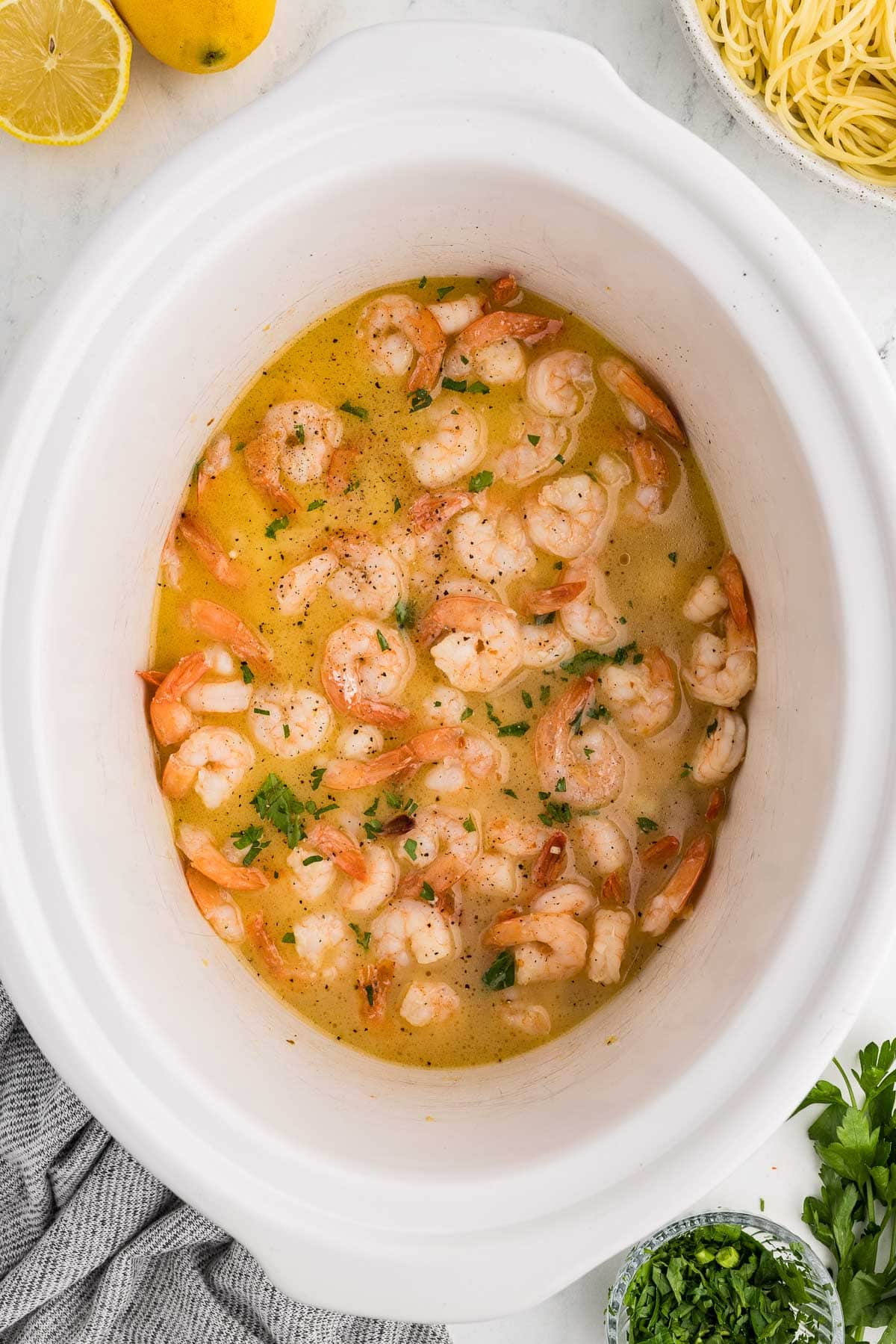 Add shrimp, olive oil, butter, wine, garlic, salt, pepper and red pepper flakes to slow cooker in process of being cooked in slow cooker