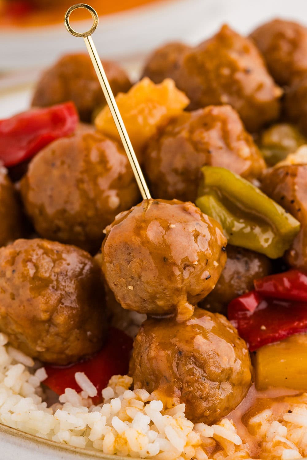 Close up of Slow Cooker Sweet and Sour Meatballs with a tooth pick inside of meatball
