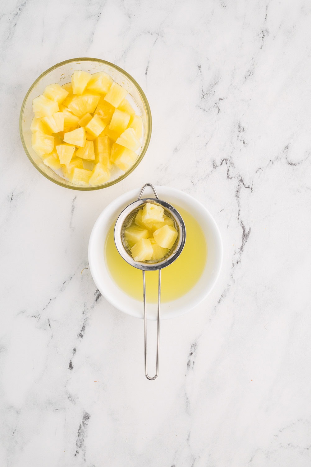 Pineapples being strained into bowl