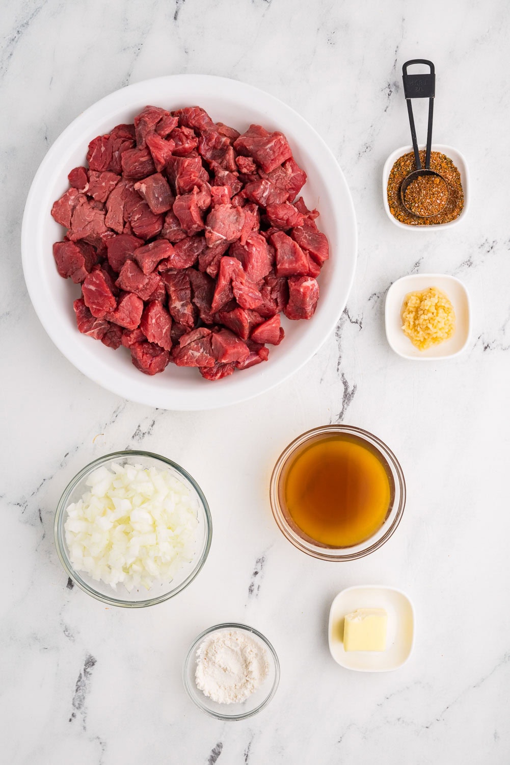 Ingredients like 2 pound beef or bison stew meat 2 teaspoons flour (can be gluten-free) 2 tablespoons pot roast seasoning or steak seasoning (homemade or store bought) 1 small sweet onion, chopped 1 tablespoon jarred minced garlic 2 tablespoons butter ½ cup beef broth all measured and laid out in counter in their respective containers