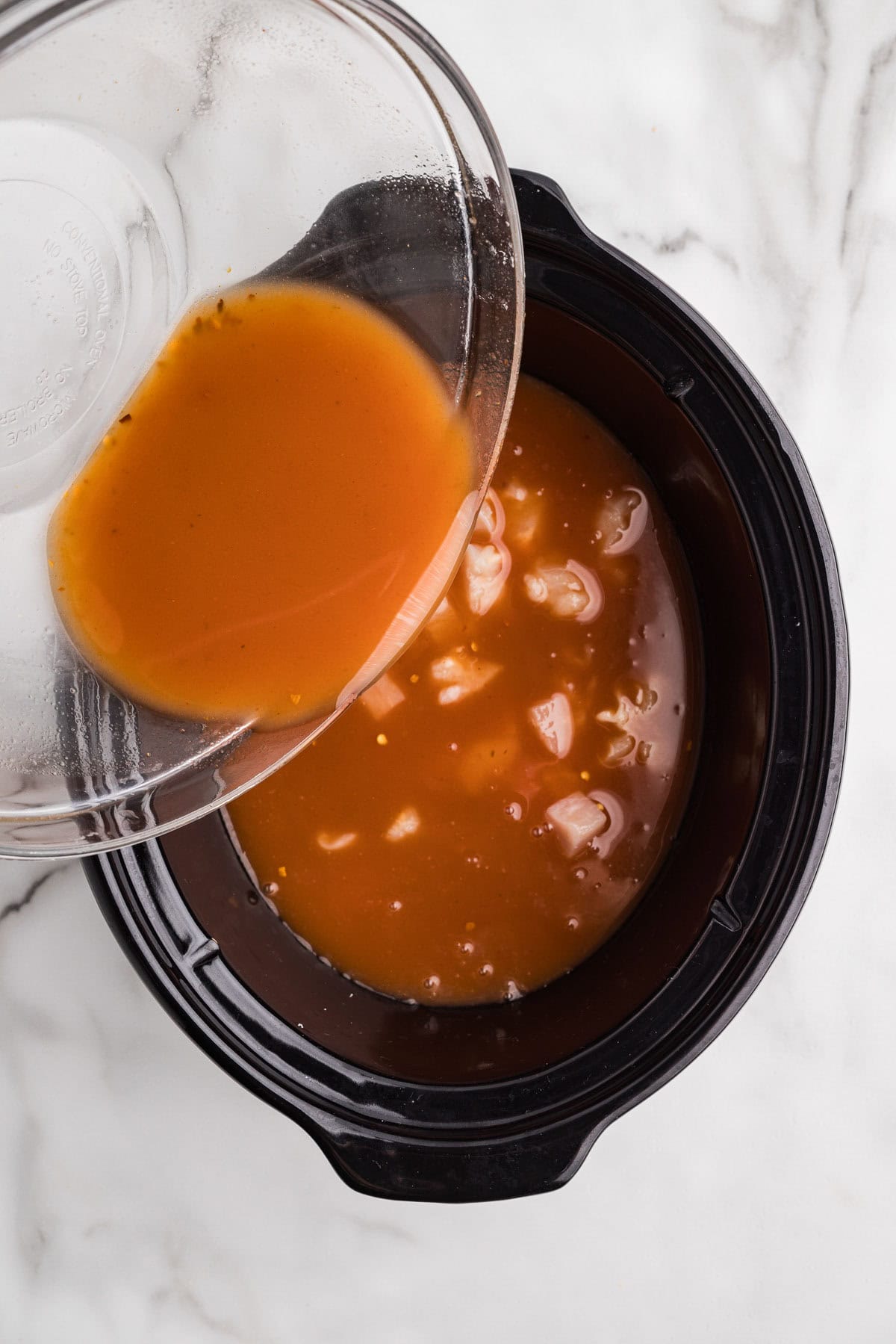Mixture being mixed into slow cooker bowl