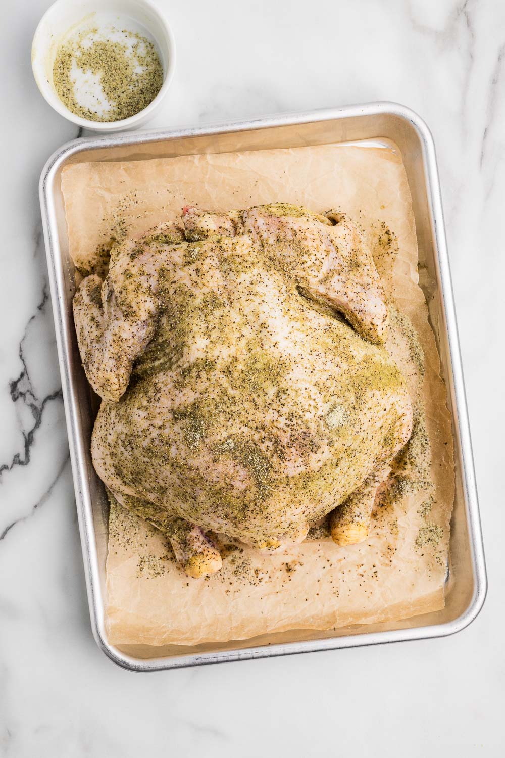 Whole chicken cut open and laying down on parchment paper