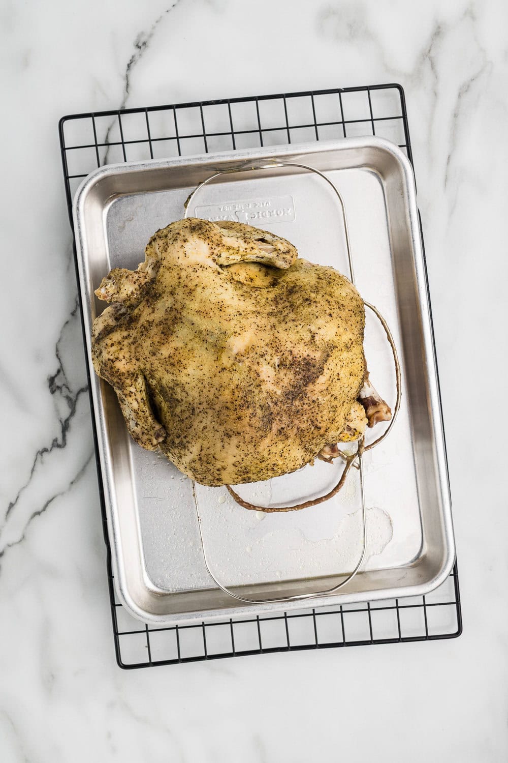 whole chicken seasoned on baking sheet