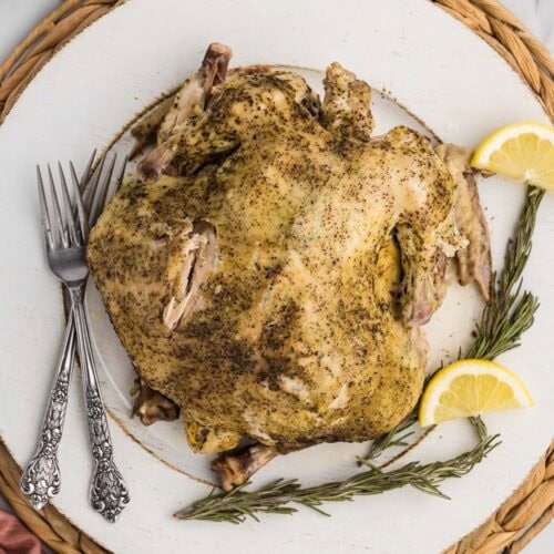 Whole chicken served on plate and garnished