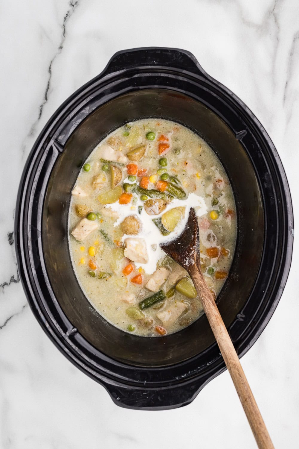 Slow Cooker Chicken Pot Pie Soup mixed in slow cooker with wooden spoon