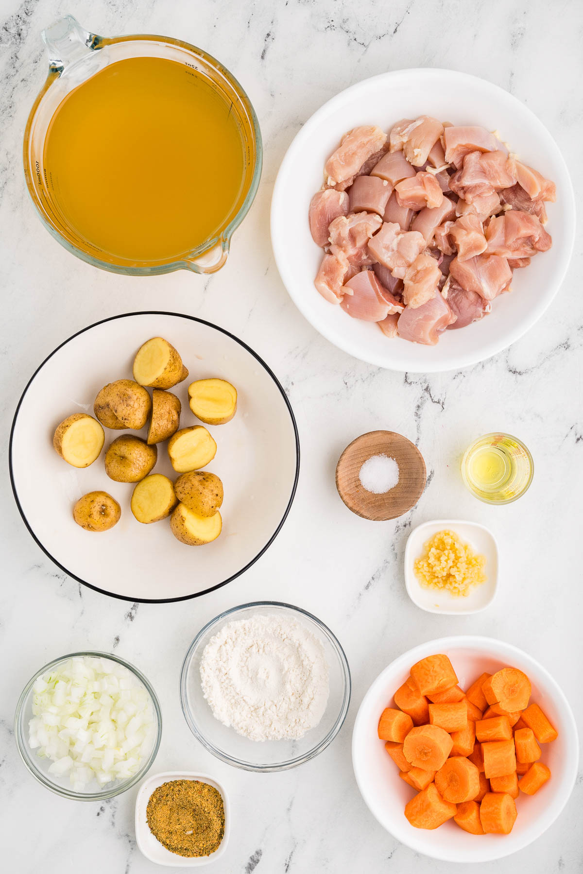 2 tablespoons olive oil 1 pound chicken thighs cut into chunks 2 tablespoons flour can be gluten-free 3 carrots peeled and sliced thick 4 baby potatoes cut into bite sized pieces 1/2 onion peeled and diced 2 teaspoons jarred minced garlic 2 teaspoons herb and garlic seasoning 1/2 teaspoon salt 4 cups chicken stock ingredients on counter ready to prepare