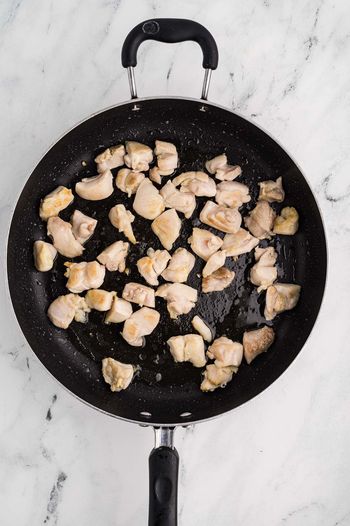 Diced chicken frying on pan