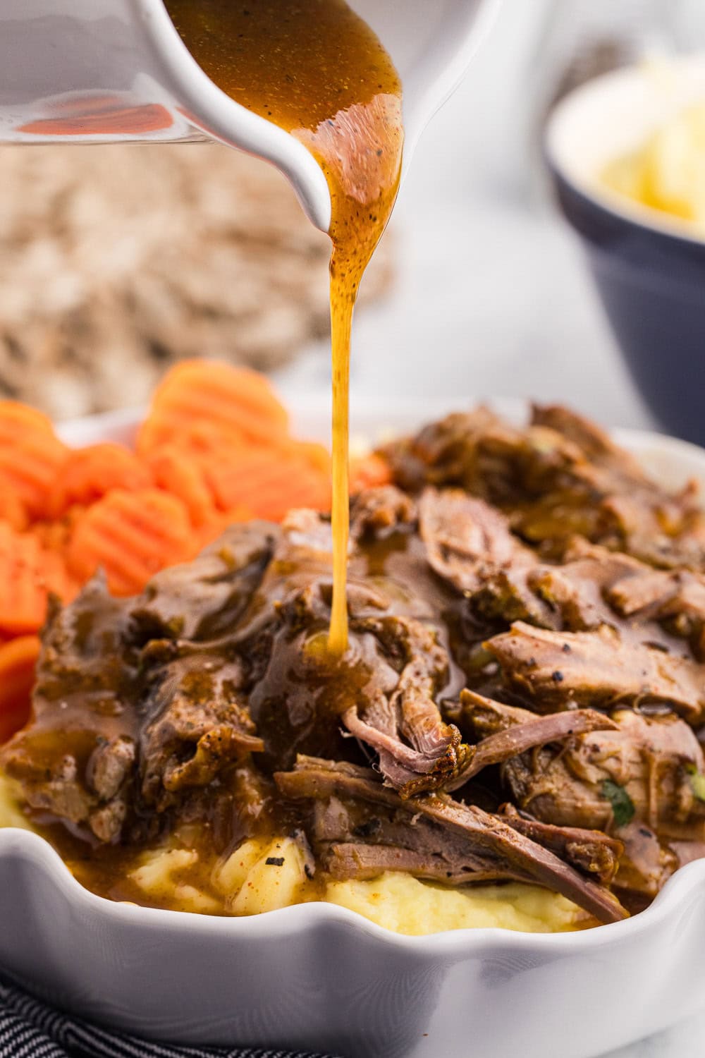 Served Slow Cooker London Broil with mashed potatoes and carrots gravy being poured on top