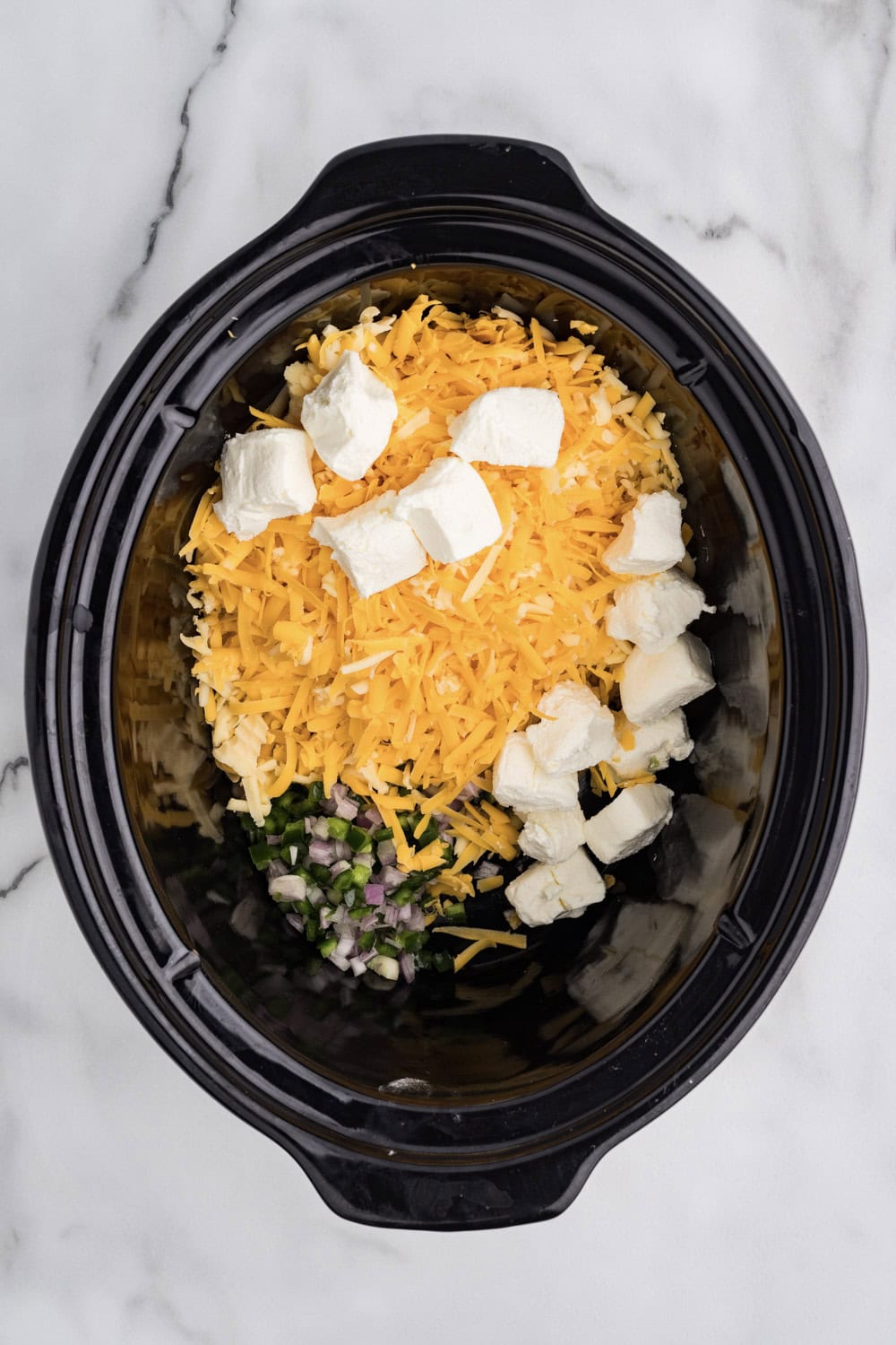 The ingredients for the cheesy cheddar dip are in a slow cooker