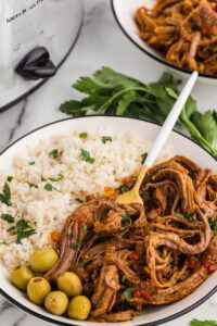 Served Easy Slow Cooker Ropa Vieja served with olives rice and garnished