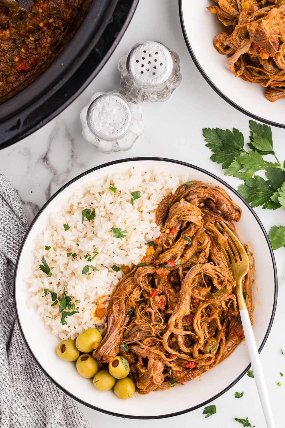 Easy Slow Cooker Ropa Vieja served with olives rice and garnished