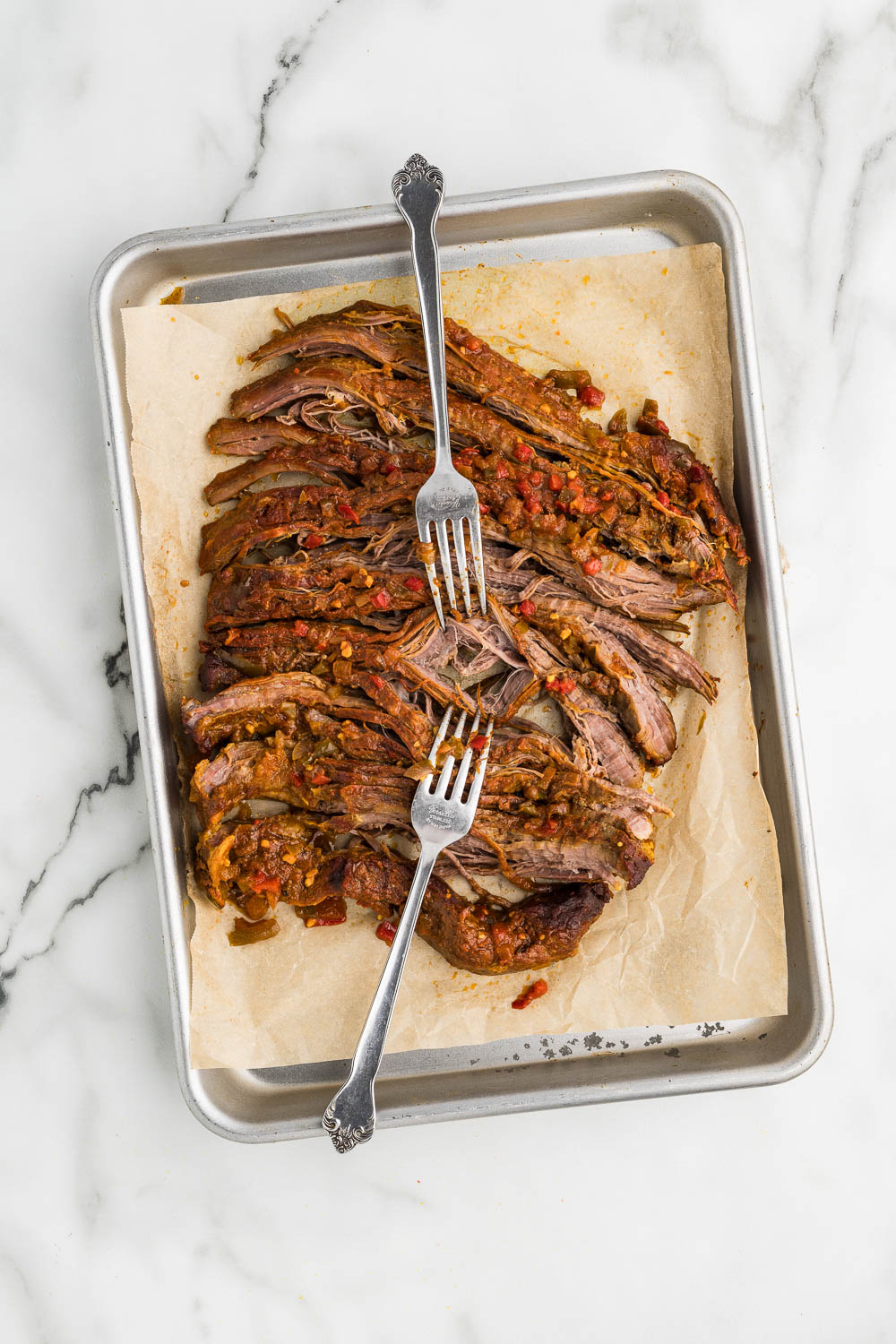 Easy Slow Cooker Ropa Vieja ready to shred on parchment paper