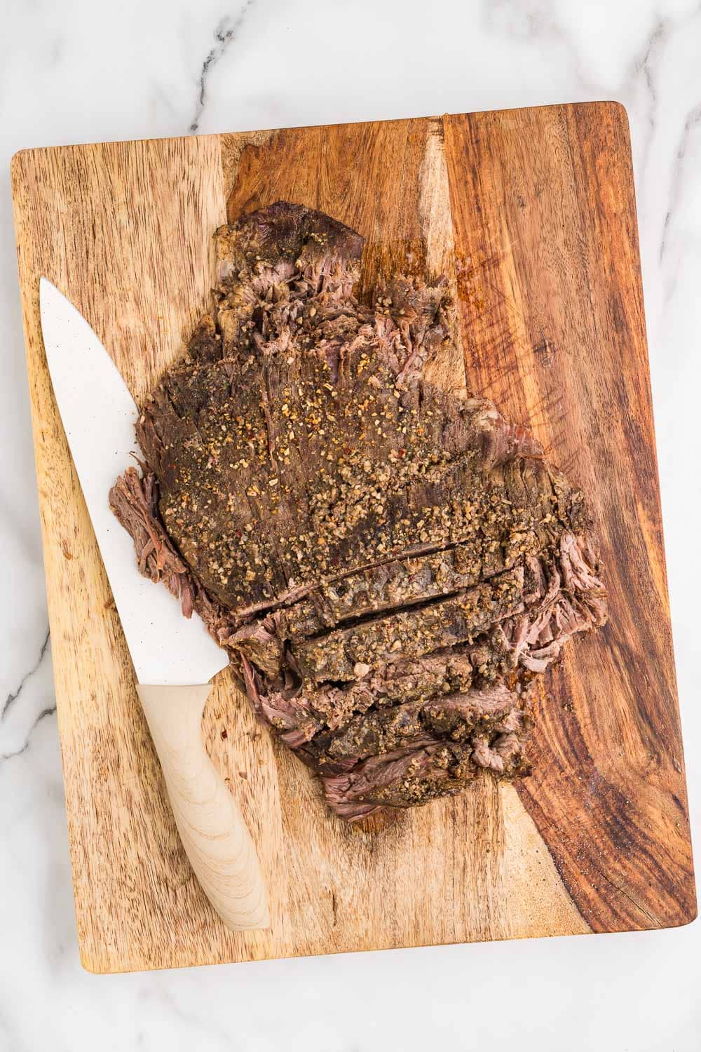 A piece of sliced steak on a cutting board with spices