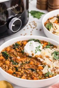 bowl of slow cooker lentil soup in front of slow cooker