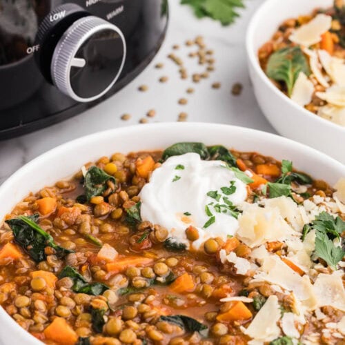 bowl of slow cooker lentil soup in front of slow cooker