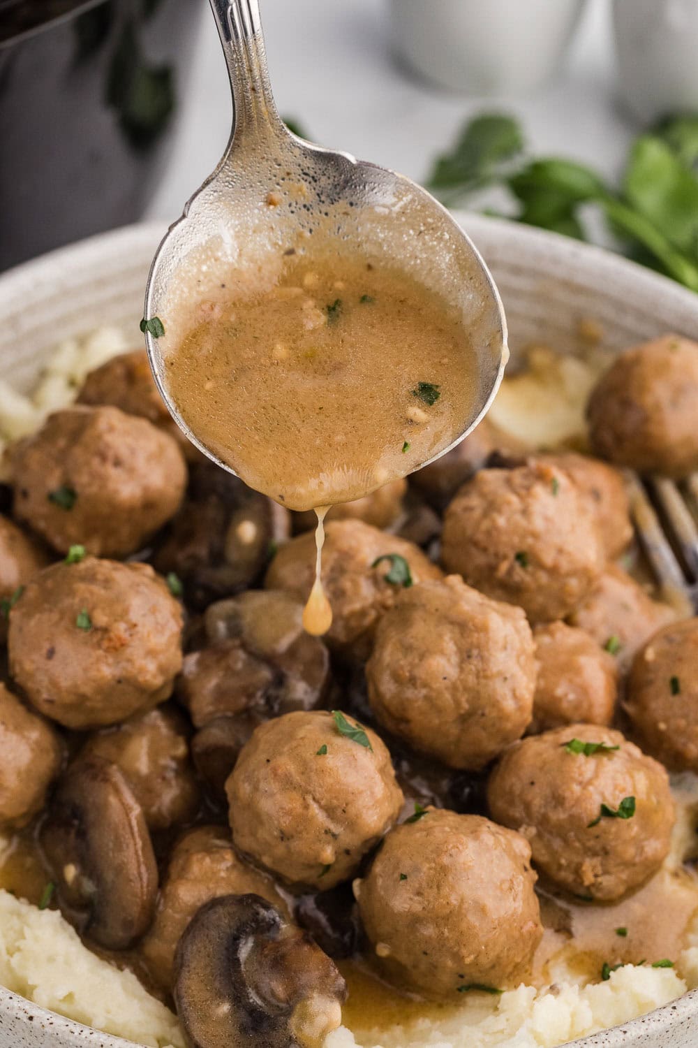 Salisbury Steak sauce being poured on top of meatballs and mashed potatoes