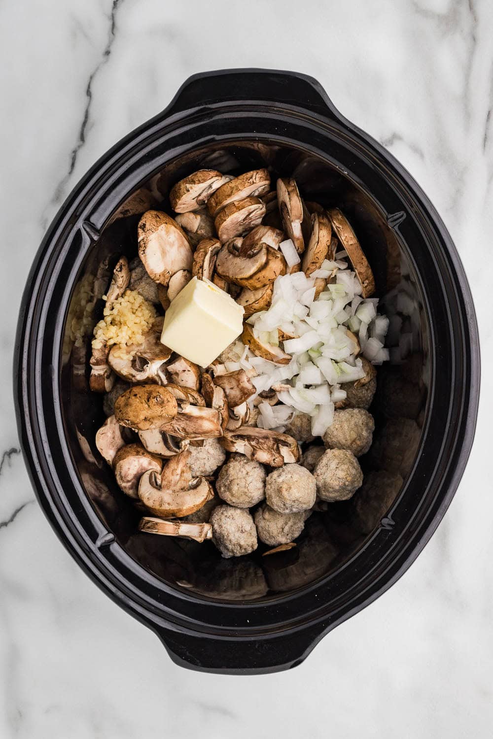 Butter mushroom onion garlic and frozen meatballs in slow cooker