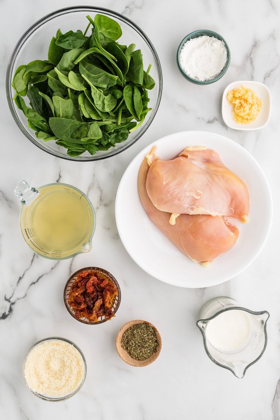 ingredients for Tuscan chicken including chicken, garlic, Italian seasoning blend, chicken stock, sun-dried tomatoes, corn starch, heavy cream, and Parmesan cheese