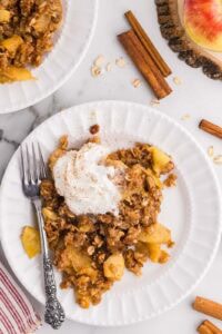 Apple crisp with cinnamon and apples on a white plate