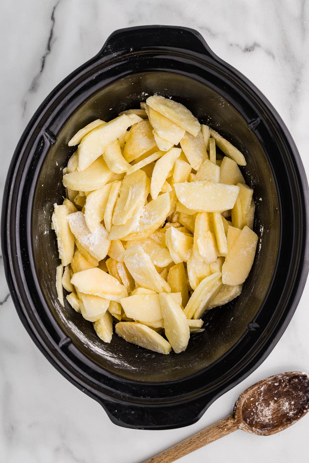 sliced apples mixed with flour in slow cooker