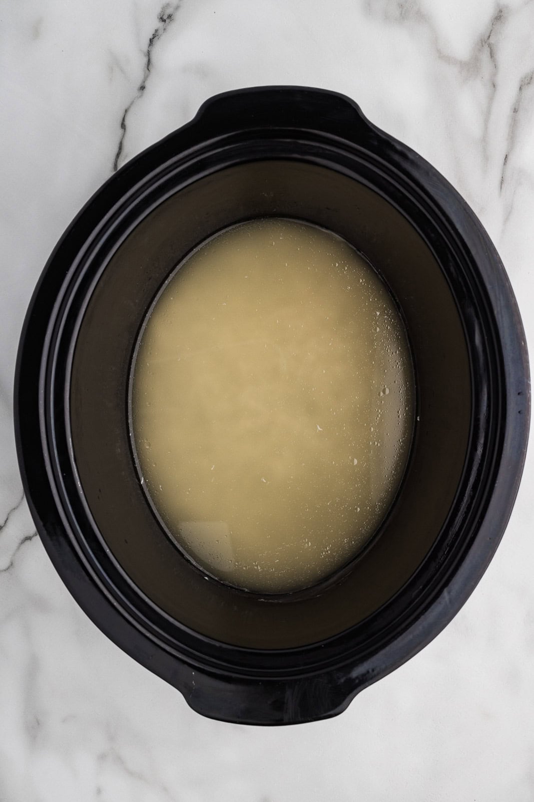 black slow cooker with rice and broth