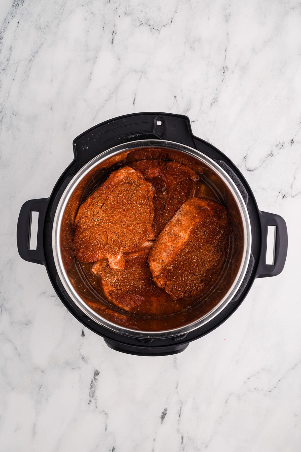 overhead shot of black instant pot with seasoned pork inside