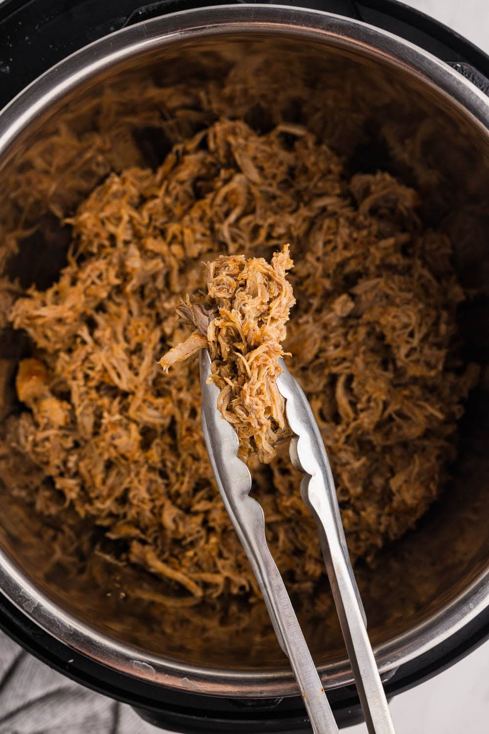 closeup of utensil holding pulled pork over instant pot with shredded pork