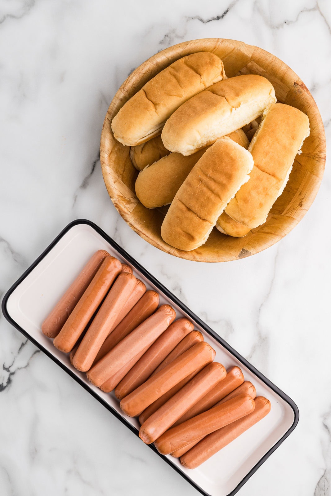 ingredients to include white plate with 24 hot dogs and basket with multiple hot dog buns