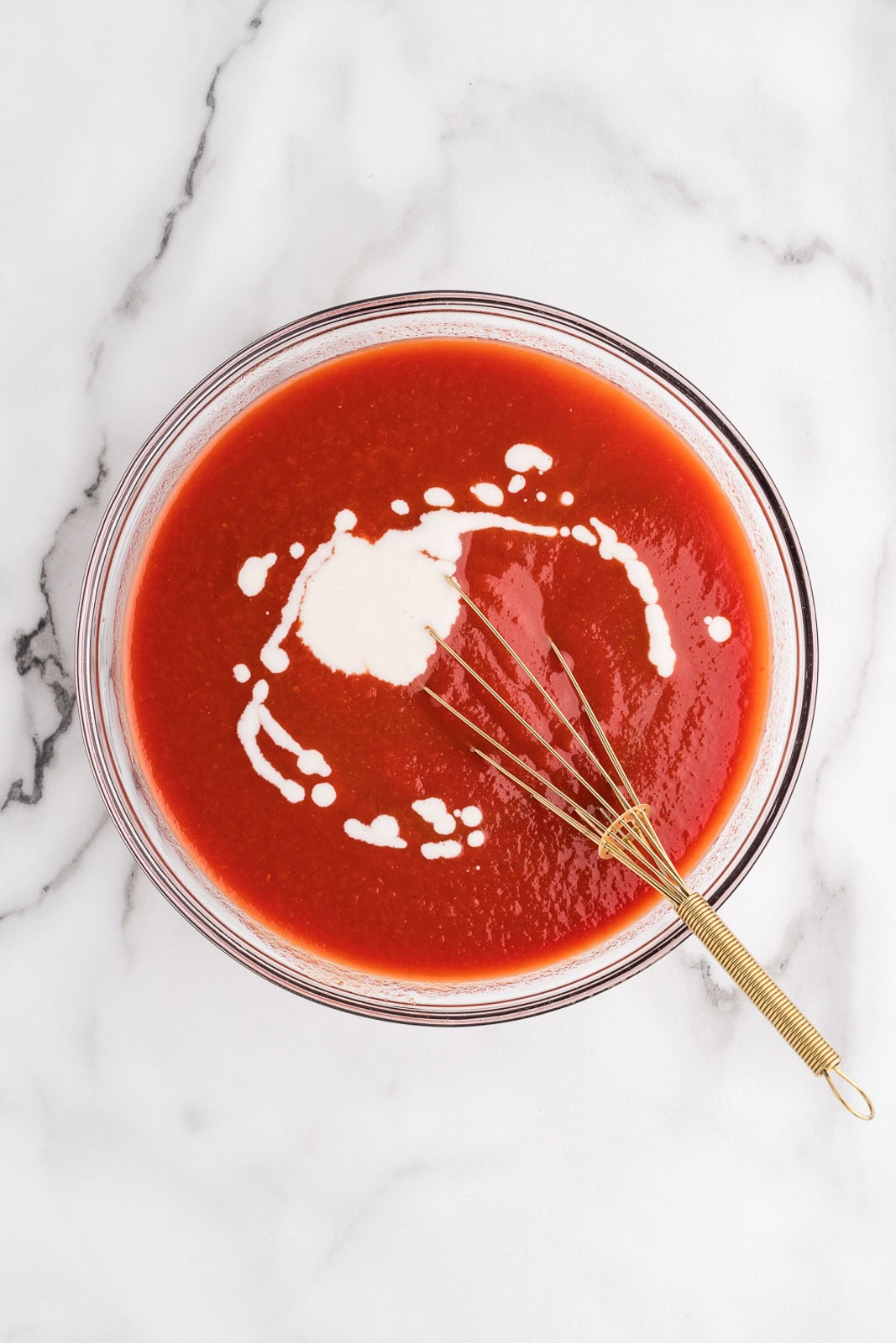 overhead view of glass bowl of tomato mixture and tapioca mixture with gold whisk