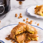 white dinner plate edged in blue with serving of French toast with caramel drizzle, with another plate, cup of coffee and black slow cooker in background