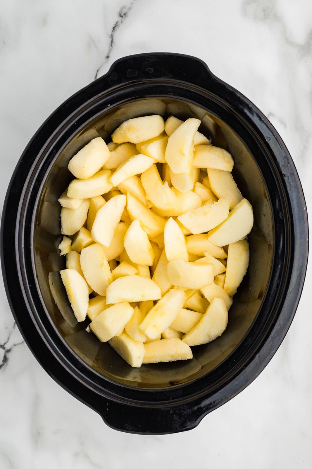 overhead view of black slow cooker with sliced apples