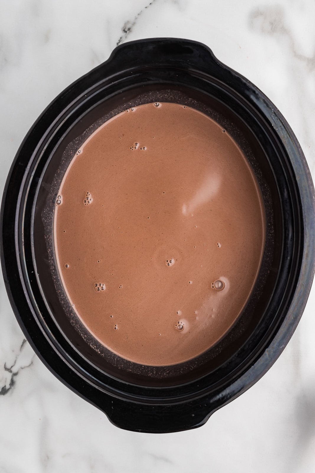 overhead view of all mixed ingredients in black slow cooker