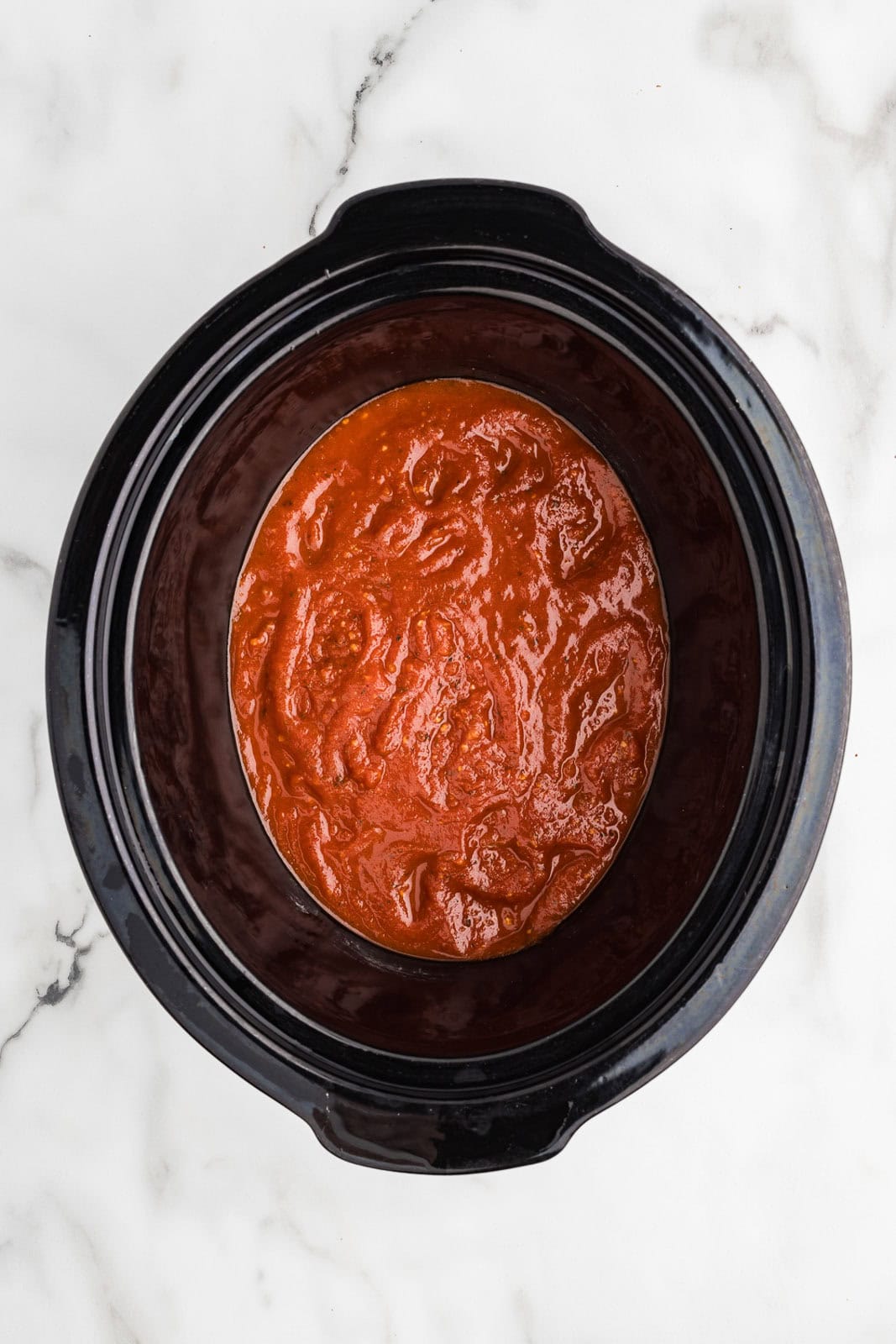 overhead view of black slow cooker with spaghetti sauce