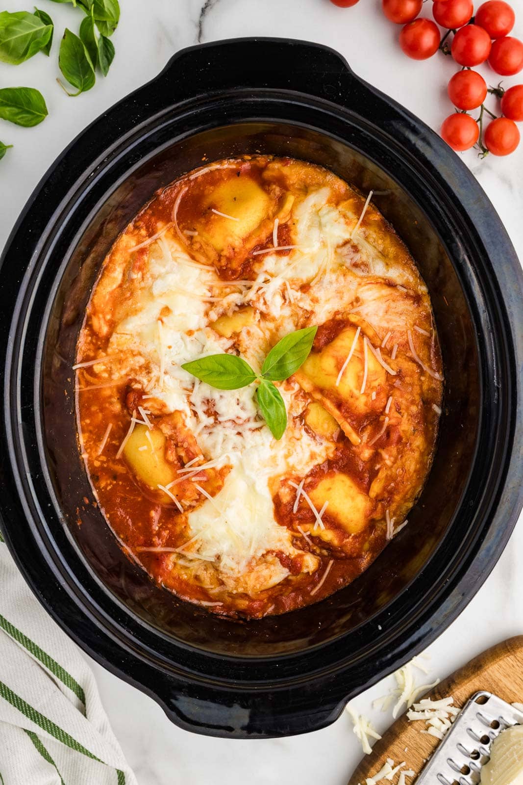 overhead view of black slow cooker with cooked ravioli lasagna