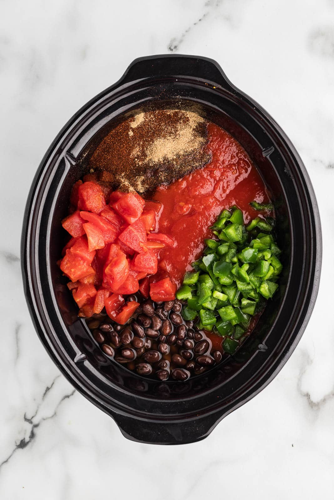 overhead view of black slow cooker containing all ingredients