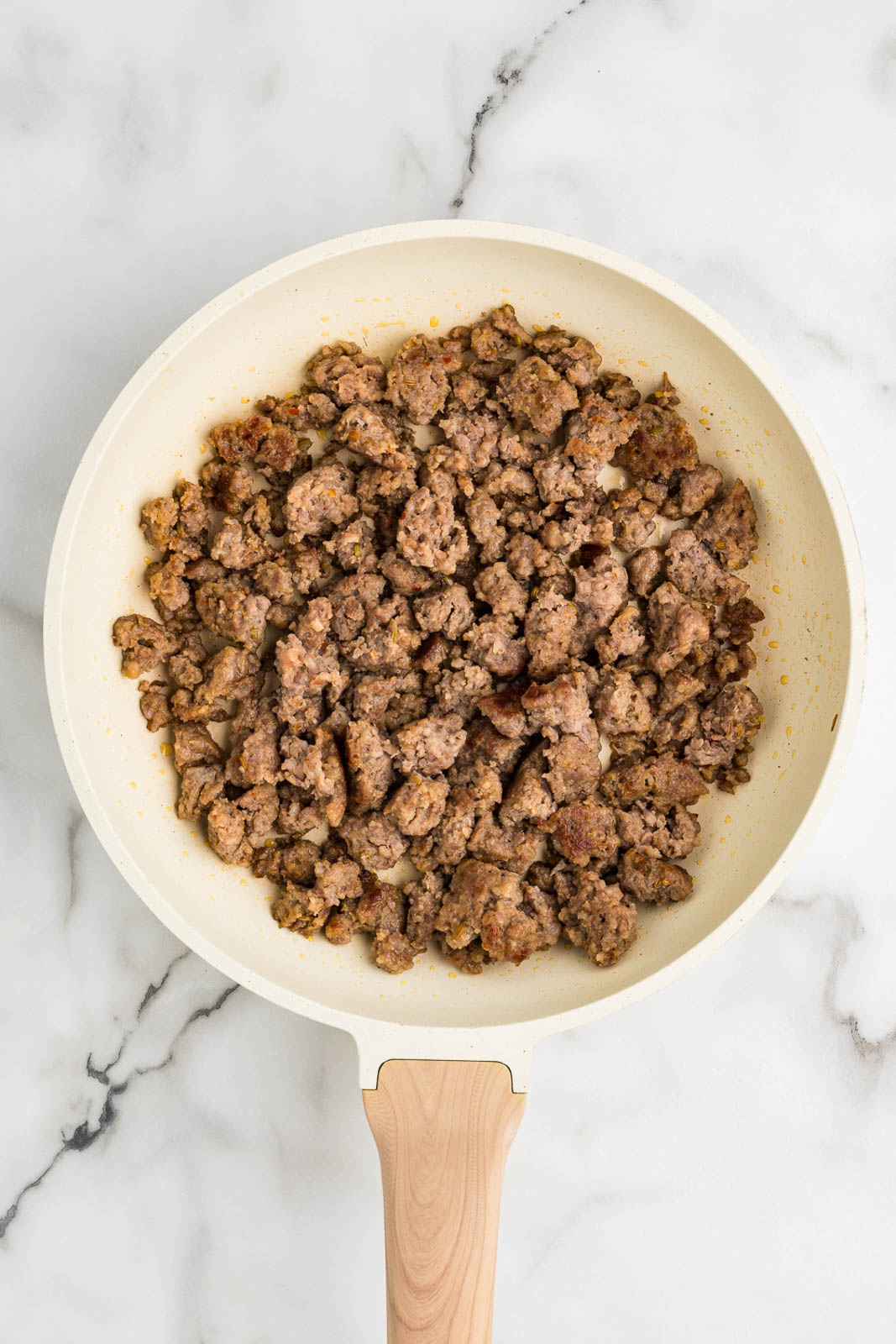 cream colored frying pan with fried Italian sausage