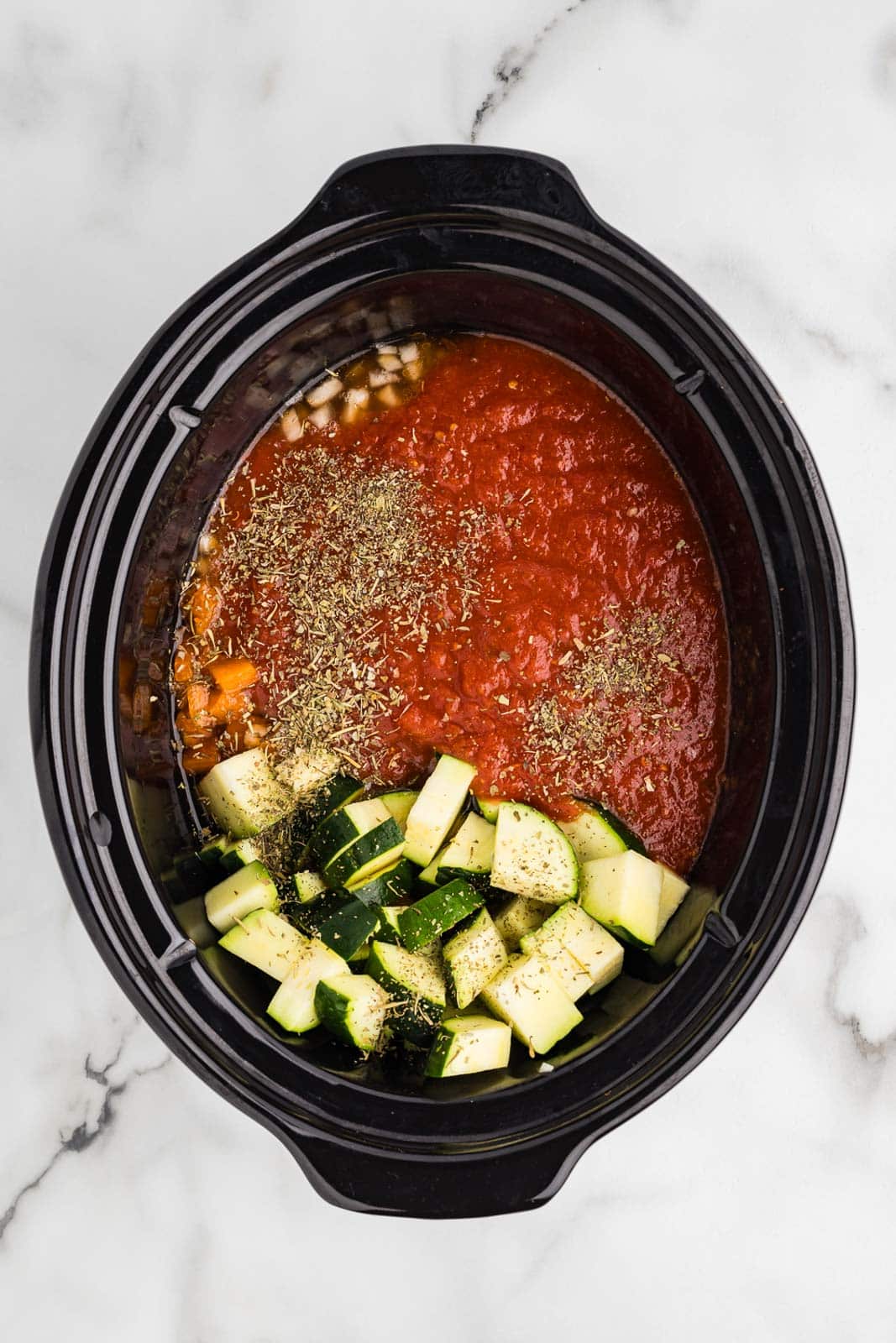 overhead view of black slow cooker of all ingredients but tortellini, cream and spinach